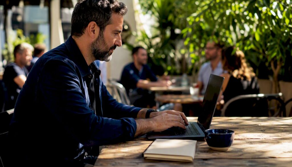 Hands scrolling on dark laptop in bright office
